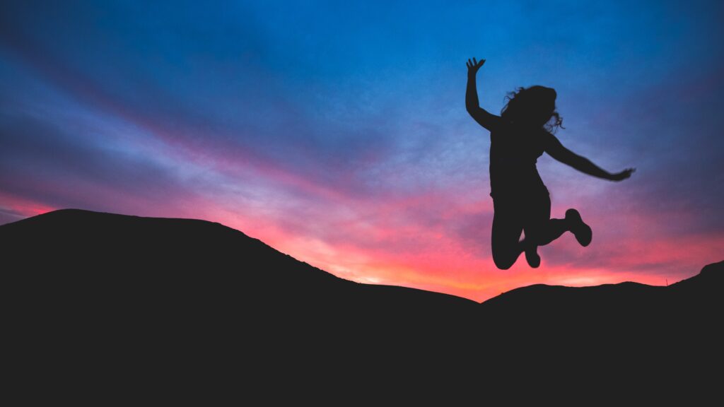 A Woman jumping in the sunset showing her joy of life, feel good from the inside out with Cassandra Austin of Casstronomy