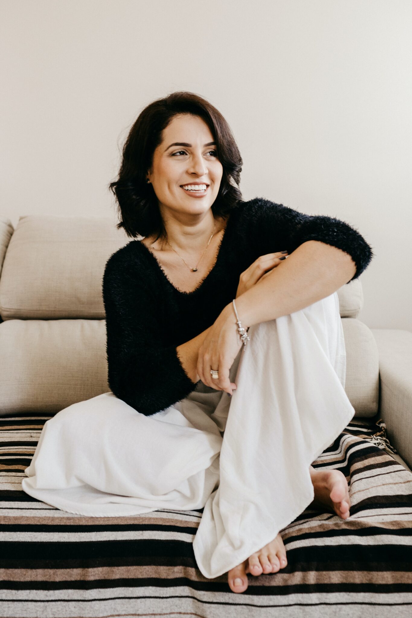 Smiling woman in midlife relaxing on a couch at home, a moment of self-care